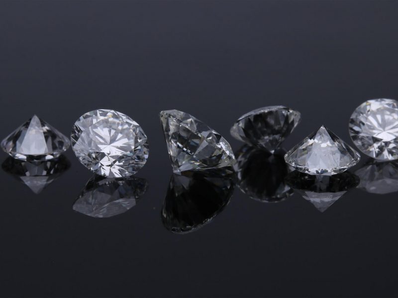 Six sparkling diamonds arranged on a dark surface.